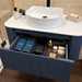Fluted wall-hung corner vanity with round sink, white countertop, and open storage