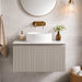 Bathroom vanity unit with ribbed front, vessel sink, and brass wall taps