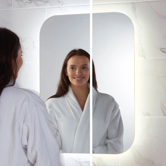 LED bathroom mirror with rounded-rectangle shape; person looks at their reflection.