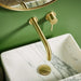 Brushed brass wall-mounted basin tap with tall spout and two small lever controls