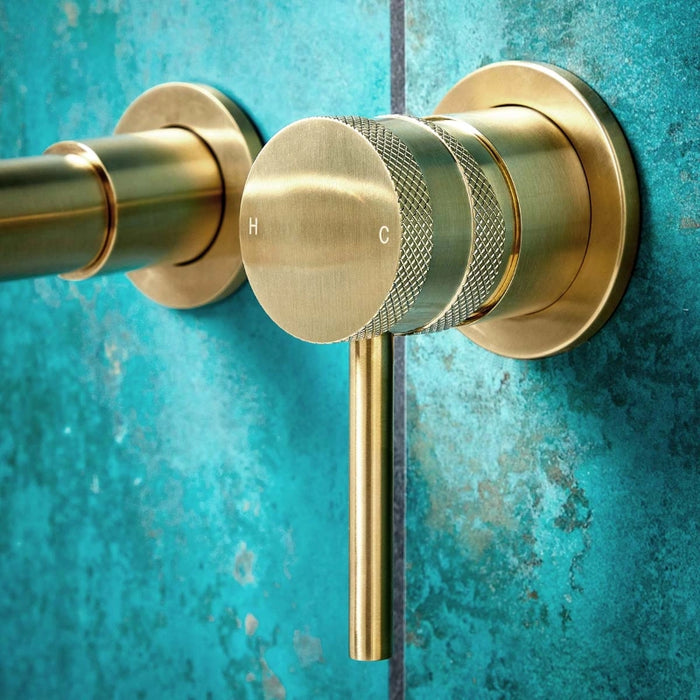 Brushed brass wall-mounted basin tap with round dial handle, H/C markings and spout