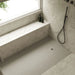 White rectangular shower tray with square waste drain in shower corner