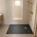 Black square slate shower tray with square waste drain, installed in a shower