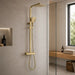 Brushed brass shower rail with square rain head, handheld spray, and hose.